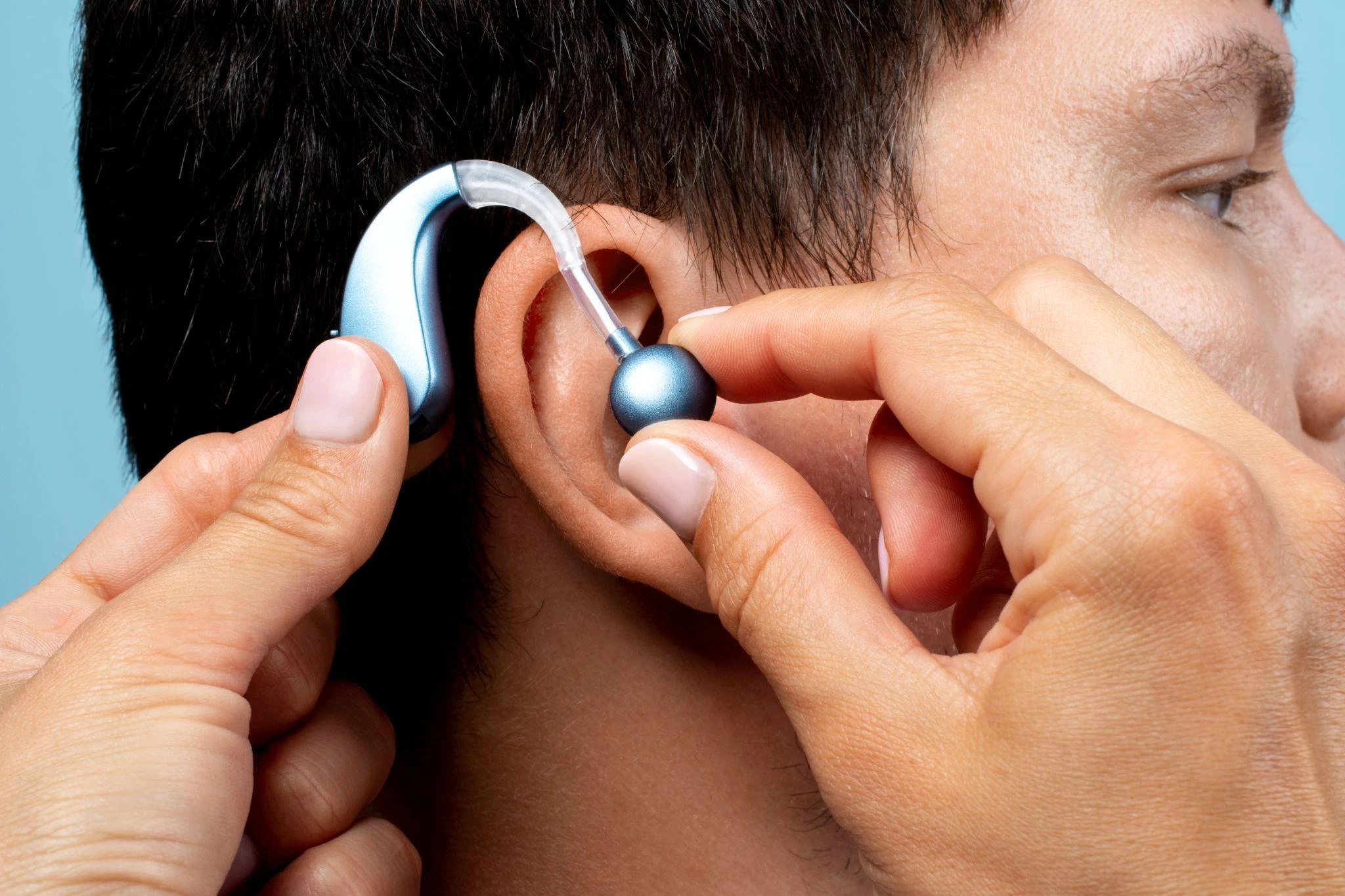 A person fitting a behind-the-ear hearing aid