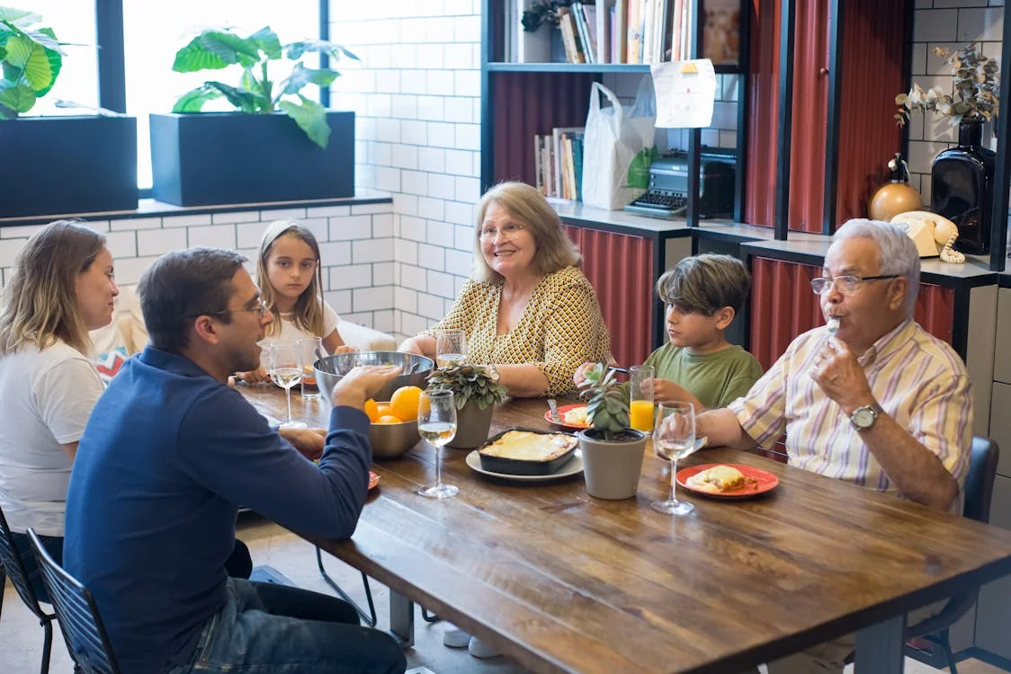 Multi-generational family with grandparents and children sharing a meal around a dinner table