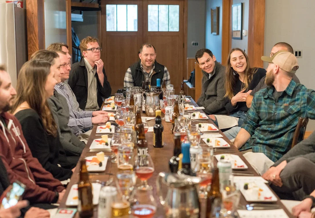 Group of friends talking and laughing over dinner at a busy restaurant table