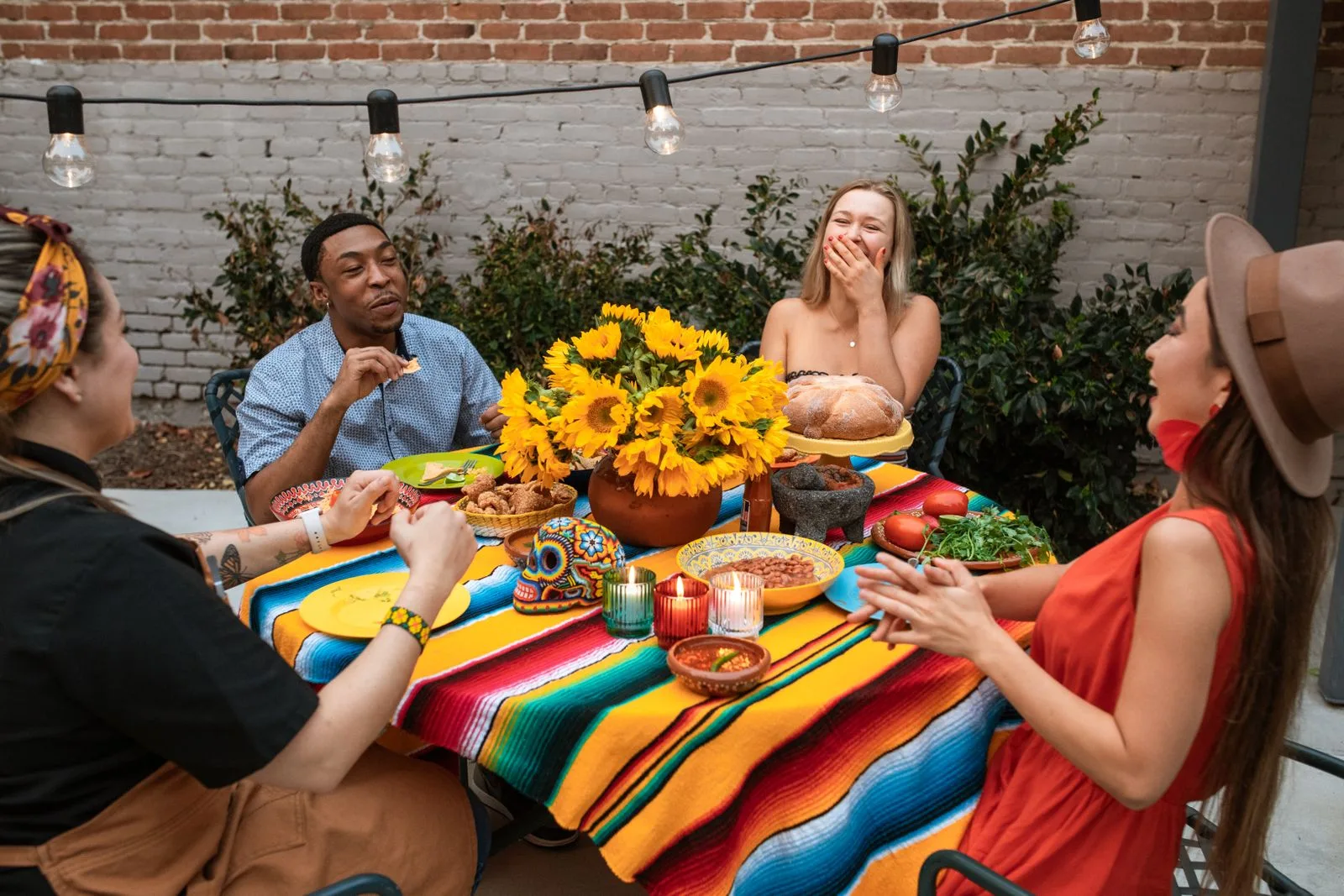 A group of friends seated around a restaurant table mid-laugh, illustrating the multi-talker noise environment where cochlear implants and captioning glasses complement each other