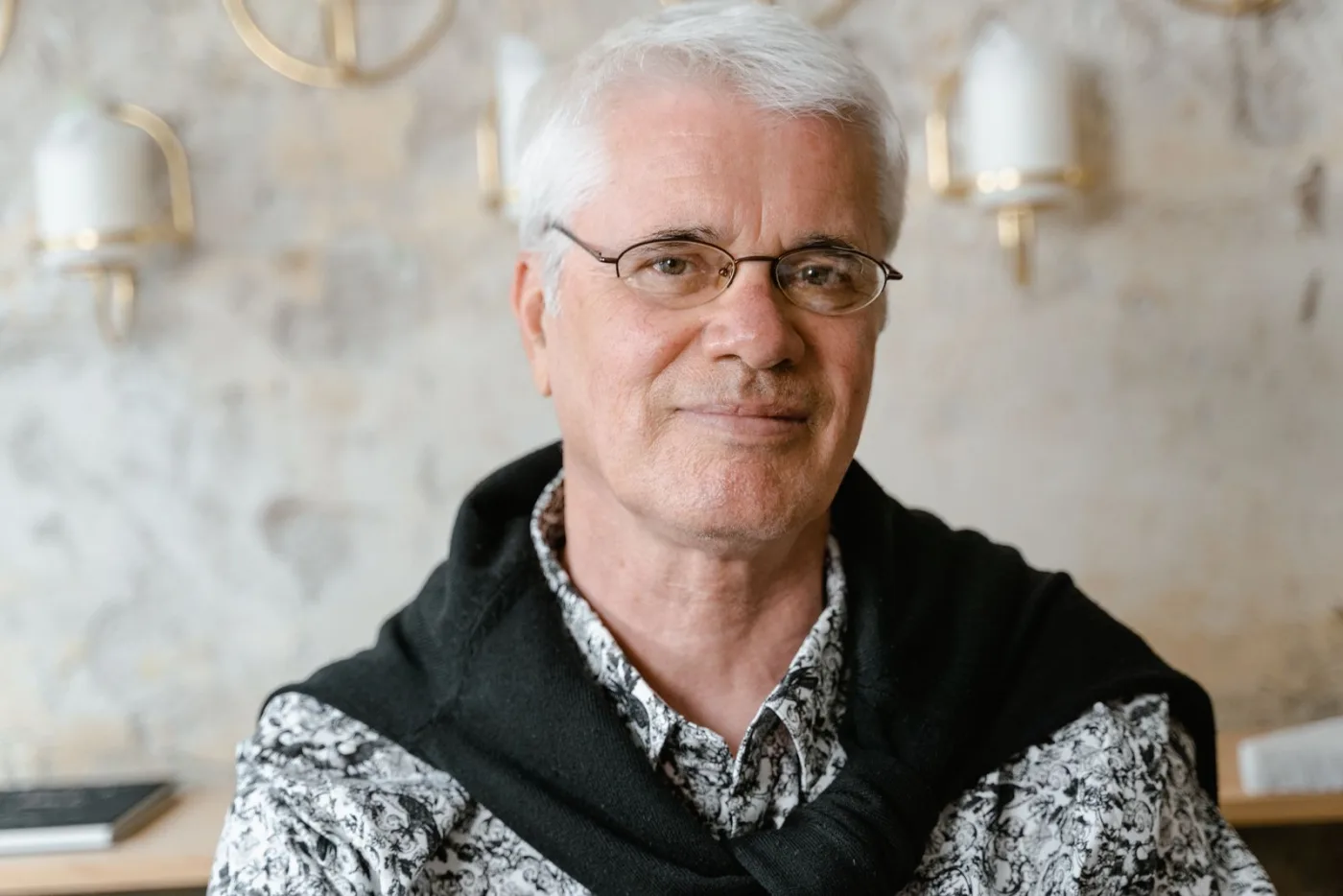Portrait of a smiling older man with white hair wearing thin wire-rimmed eyeglasses indoors
