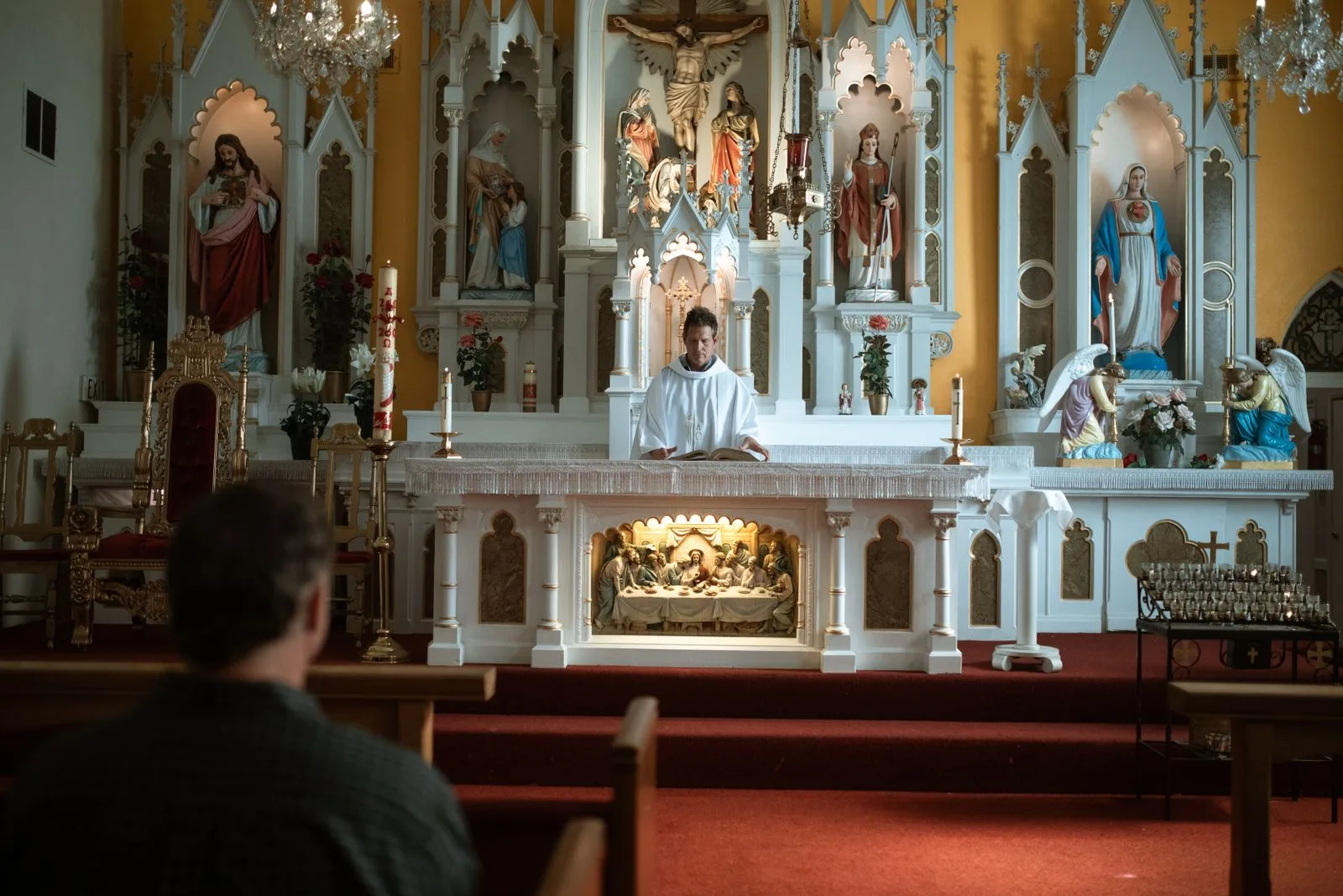 A worship service in progress with a single congregant seated in the pews facing the altar