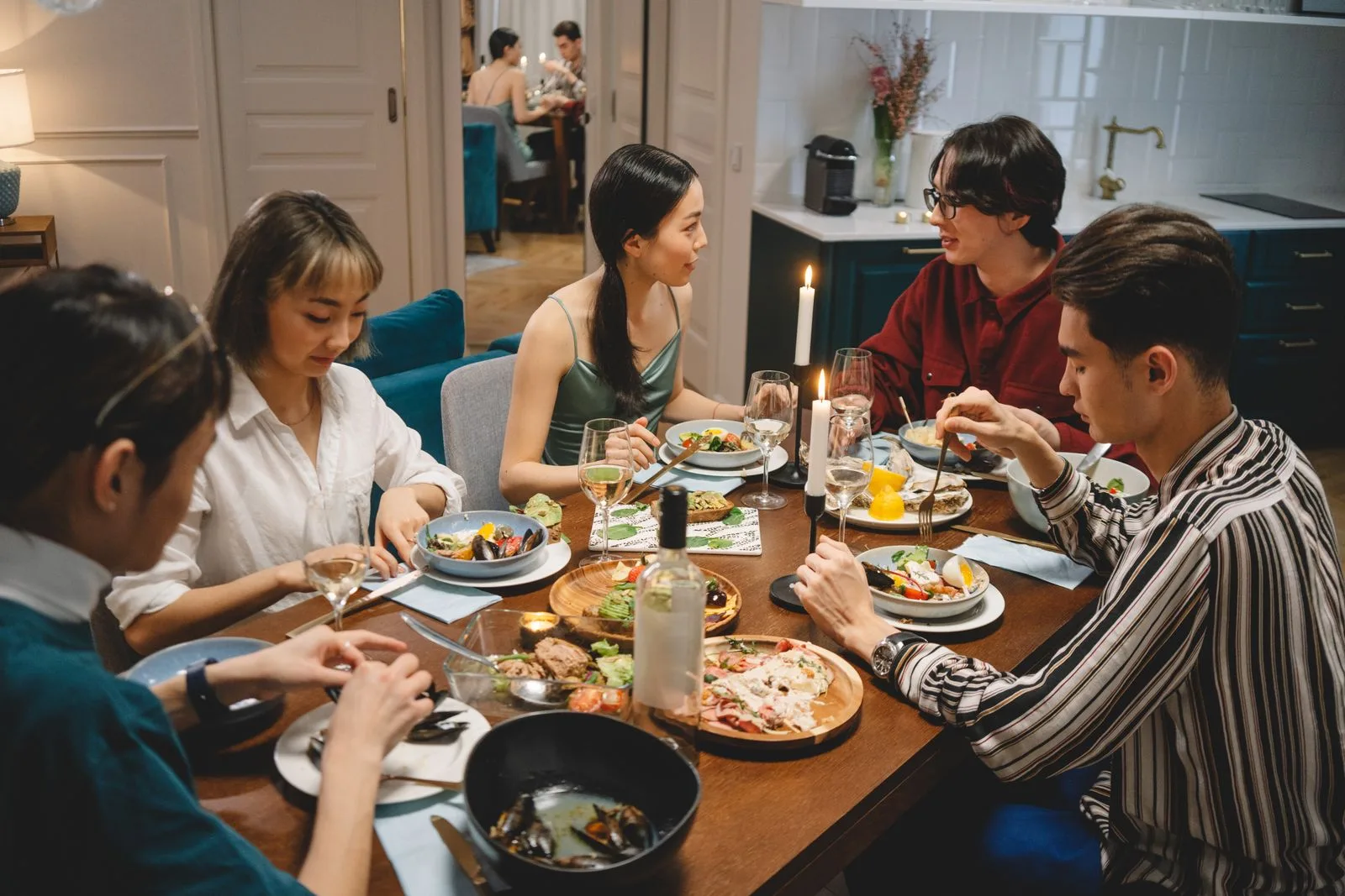 A group of friends seated around a candlelit restaurant table mid-conversation, representing the multi-talker family and social settings where captioning glasses excel for single-sided deafness